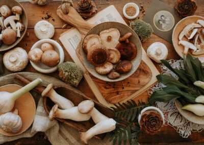Photographie culinaire mettant en scène une composition rustique de champignons frais, ail et herbes, sur une table en bois dans une ambiance automnale et naturelle. Réalisée par un photographe culinaire professionnel spécialisé dans les natures mortes.